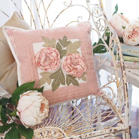 Styled shot of pink flower cushion with pleating, appliqué leaves and 3d fabric flowers