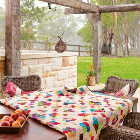 Styled shot of multi-coloured geometric flower quilt on table in country scenery