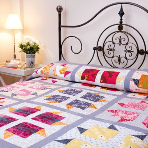 Styled shot of geometric block flower quilt on bed