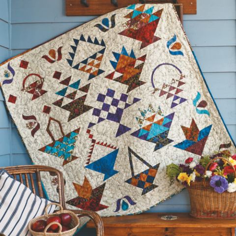 Styled shot of patchwork and appliqué basket quilt sampler hanging up with baskets