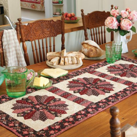 Styled shot of tablerunner with three dresden patchwork flowers on table with accompanying food
