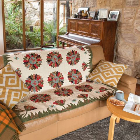 Styled shot of quilt on lounge in living room with large daisies and grass edging