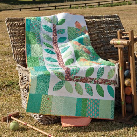 Styled image of patchwork quilt with tree and birds sitting on chair with croquet set