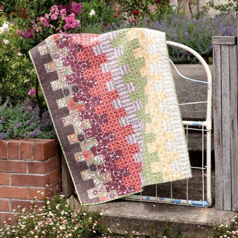 Styled shot of ladder patterned quilt draped over gate in garden