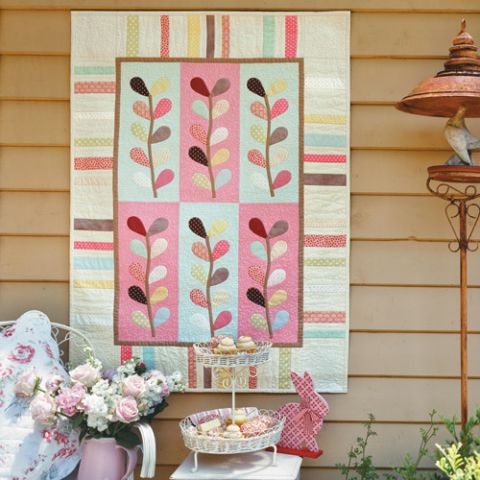 Styled shot of gelato appliqué and patchwork wallhanging and cot quilt hanging up