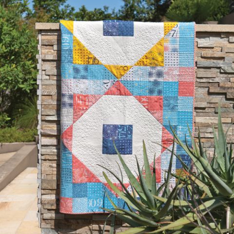 Styled shot of colourful octagon patterned patchwork quilt hanging on rock-work outdoors