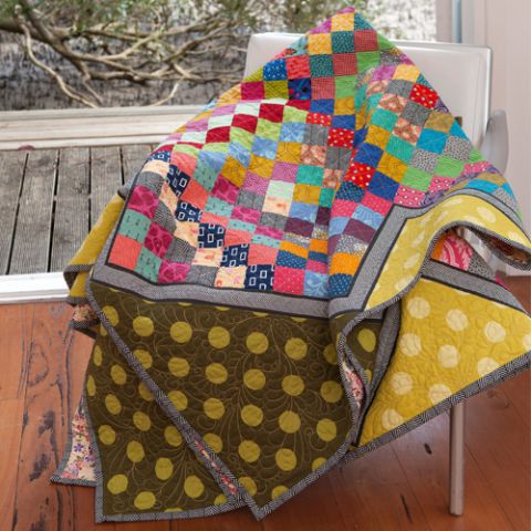 Styled shot of colourful square patterned patchwork quilt lying on chair 