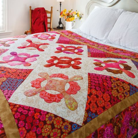 Styled shot of modern appliqué quilt on bed