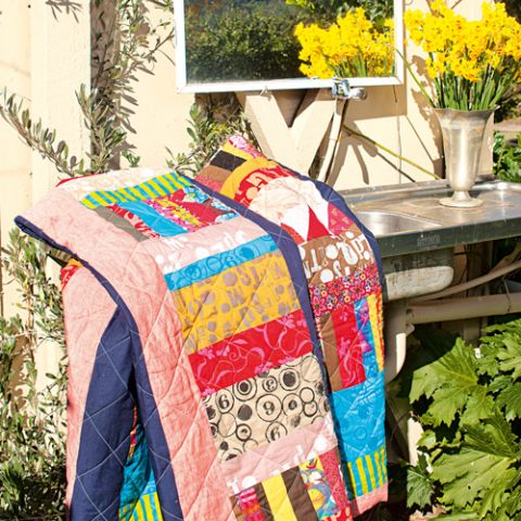 Styled shot of colourful patchwork quilt draped on table in rustic outdoor area