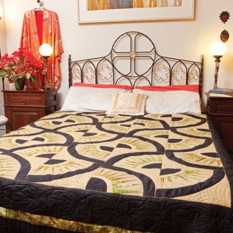 Styled shot of black and gold patterned quilt in bedroom