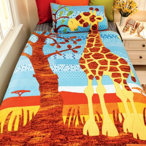 Styled shot of appliqué giraffe quilt and cushion set on bed