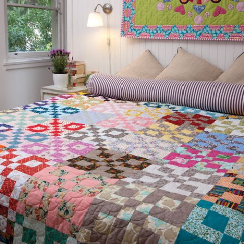 Styled shot of colourful square patterned patchwork quilt in bedroom 