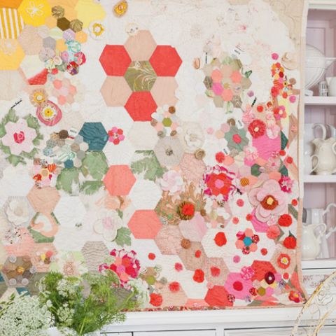 Styled shot of scrappy garden art quilt hanging up