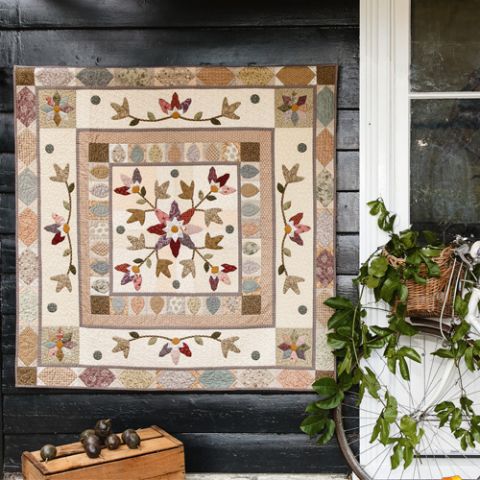 Styled shot of traditional-style appliqué medallion quilt hanging up 