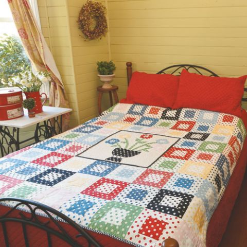 Styled shot of polka dot appliqué flower quilt on bed