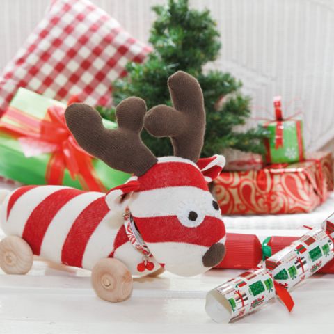 Styled shot of christmas reindeer sock toy softie with christmas gifts and tree