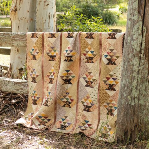 Styled shot of geometric basket patterned quilt on fence outdoors