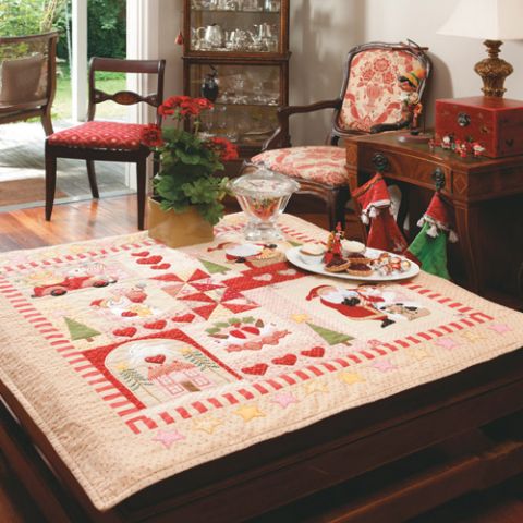 Styled shot of appliqué, patchwork and embroidered christmas wallhanging quilt on table