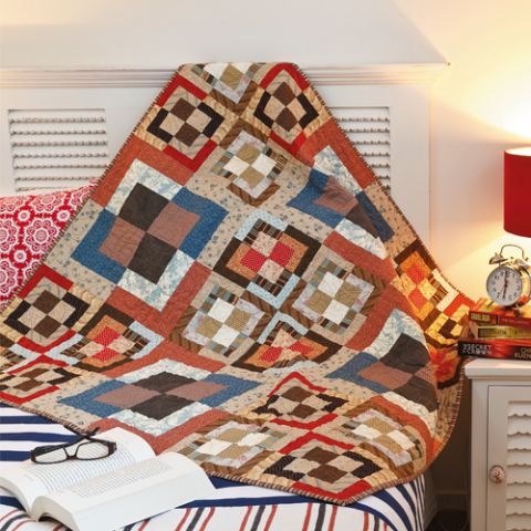 Styled shot in bedroom of square patterned patchwork quilt