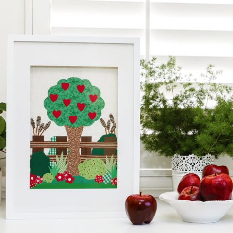 Styled shot of framed applique tree with love hearts, flowers, fence and shrubs
