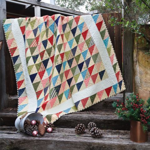 Styled shot of half-square triangle quilt draped over railing